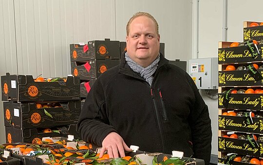 Großhändler Ralf Albers vor Kisten mit Clementinen